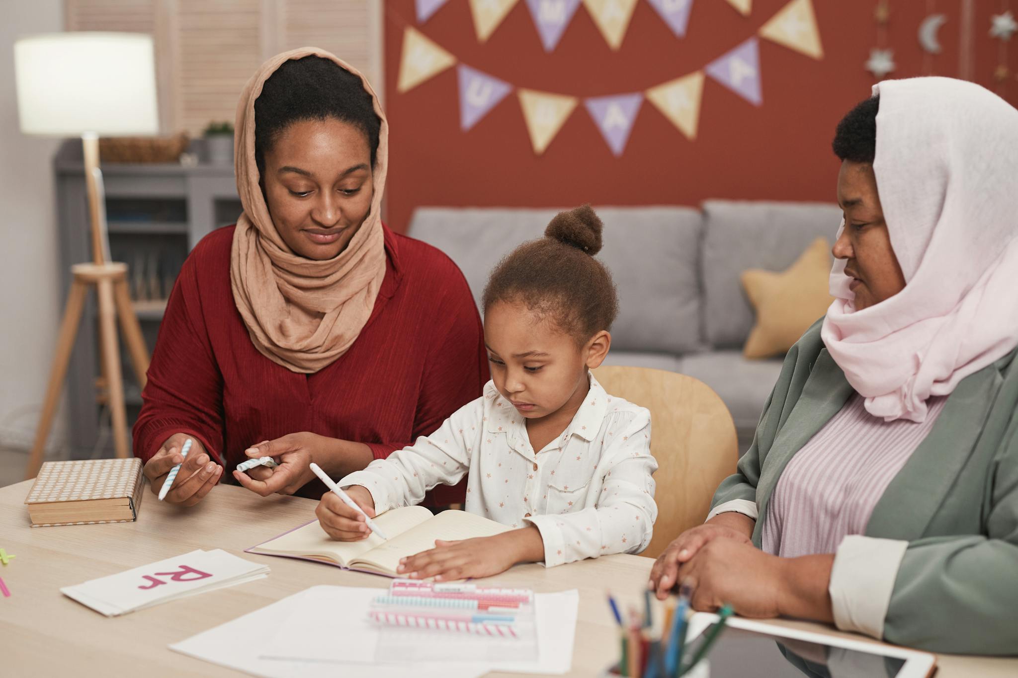 A child learning and drawing with two adults guiding her in an indoor setting.