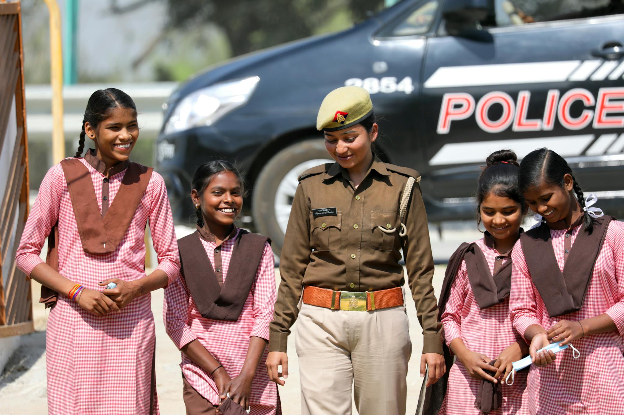 A police officer shares a moment with smiling girls in uniform outdoors.